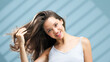 © wedmoments.stock - Young woman with healthy skin and flowing hair, smiling while playfully tossing her hair in a bright, airy space, showcasing a vibrant atmosphere and emphasizing the beauty of skincare and self-care