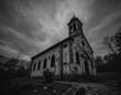 © Anum - Eerie abandoned church stands under a dramatic, stormy sky.