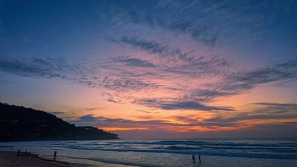 Wall Mural - Time lapse A stunning scene of a vivid sunset with pink and orange hues illuminating the sky over Karon beach Phuket. The serene water reflection create a peaceful and atmospheric view.