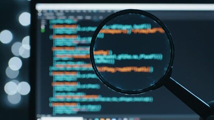 Magnifying Glass Over Computer Code in Blue Lit Dark Room with Bokeh Background