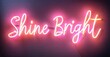 © antishock - Pink neon sign displays Shine Bright script. Background is dark purple, creating vibrant contrast. Simple, motivational message.