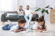 © New Africa - Kids drawing near their parents on warm floor at home, selective focus. Heating system