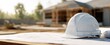 © Kovalenko - The white hard hat resting on construction plans at a busy job site.