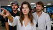 © Samuel - Young woman pointing at monitors displaying data analysis charts while colleagues watch closely, collaborating on strategic planning in modern office