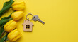 © Iram - A house key with a wooden house keychain and yellow tulips on a bright yellow background for real estate