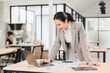 © PRIME STOCK LAB - Confident businesswoman in gray suit working on laptop in modern office, analyzing financial charts and documents on desk, professional and focused atmosphere