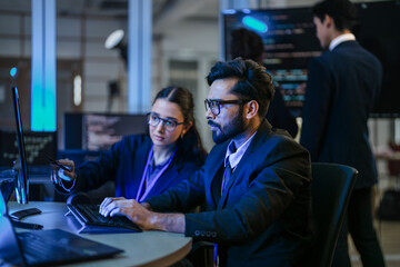 A diverse team of AI developers shares a successful moment in the office. A female programmer smiles as they review the positive results of a complex machine learning algorithm.