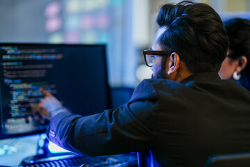 A backend AI developer programs a complex algorithm late at night in a data center. A focused engineer architecting a new machine learning system for data analysis or cybersecurity.