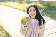 © luismolinero - Young woman with an apple at outdoors with surprise and shocked facial expression