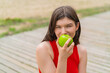 © luismolinero - Young pretty woman at outdoors eating an apple