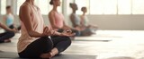 The yoga class of women meditating on mats in a serene sunlit studio space