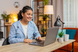 © Andrii Iemelianenko - Young woman wearing headset, freelance worker, call center or support service operator helpline talking with client or colleague communication support. Girl using laptop at home office desk. Lifestyle