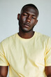 © Nelover - Dark Brazilian Male Model in Light Yellow T-Shirt on Minimalist White Studio Background, Relaxed Pose, Fashion Lighting