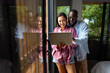 © NDABCREATIVITY - Happy young diverse, multiethnic couple planning budget, reading good news on laptop at home