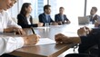 © Harumus - Businesspeople seated around a conference table, signing documents.