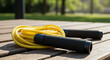 © Ruqia - Jump into Fitness: Yellow Speed Rope on Wooden Deck. This image captures the vibrant energy of fitness with a bright yellow speed rope resting on a warm, weathered wooden deck.