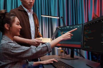 IT developers discussing with point to intelligent website development coder system running data online two screens information technology at neon light room at modern office. Infobahn.