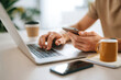 © Alina - Hands typing on a laptop while holding a smartphone in a modern work setting