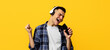© Prostock-studio - Emotional young man in headphones listening to music, singing song, using smartphone as mic on orange background. Millennial guy in headset pretending to be rock star, enjoying his favorite playlist