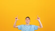 © Prostock-studio - Joyful young guy pointing upwards at blank space for your advertisement on orange studio background. Handsome millennial man promoting your product. Sale or discount concept
