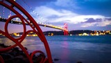 A scenic view of the Bosphorus Bridge at twilight, framed by ornate red metalwork.