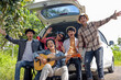 © Gatot - Happy Friends Cheering Against a Car Open Trunk on Nature. Road Trip Concept.