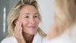 © Johannes - happy 50s middle aged woman model touching face skin looking in mirror smiling mature older lady pampering enjoying healthy skin care aging beauty skincare treatment cosmetic products concept no logo