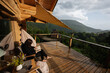 © AS Photo Family - Woman reading on a cozy wooden terrace with scenic mountain views