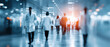 © Denniro - Blurred conceptual image of doctors walking in hospital corridor. Group of medical professionals in white coats moving through a modern clinical hallway