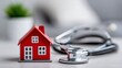 © NovaVision - A red house model and a stethoscope represent home health or property assessment.