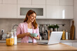 © Graphicroyalty - woman in a cozy kitchen prepares a healthy breakfast, pouring milk into a bowl of cereals. She enjoys a peaceful morning routine, embracing a nutritious start to the day.