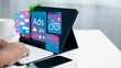 © Thawatchai Images - Person using tablet with digital ads, AI, social media, and data analysis interfaces symbolizing online advertising and modern marketing technology