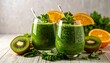 © SnapGlint - Two glasses of vibrant green smoothie garnished with orange slices, surrounded by kiwi, cucumber, kale, and halved oranges—bright, fresh, and nutrient-rich on clean white background.