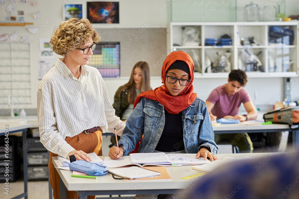 Teacher helping female student with hijab during lesson Stock Photo ...
