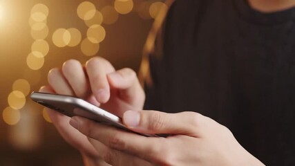 Close Up of Person Using Smartphone with Bokeh Background in Golden Warm Light