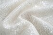 © TheWaterMeloonProjec - Macro shot of a detailed white textile featuring fine metallic fibers and an even weave pattern.