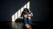 © phj.domingos - Image of sad woman sitting alone in dark room with light depicting mental health struggles concept violence against women.
