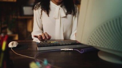 African American female employee typing on keyboard in 80s style office
