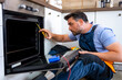 © Marko - Technician repairs oven in modern kitchen while measuring appliance components
