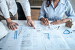 © Thitiphat - Team of architects or engineering consulting and analyzing working on objects tools and construction drawings inspection, discussing planning new architectural project on blueprint and model house