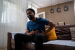 © Nenad - Young man suffering from stomach pain while sitting at home in living room