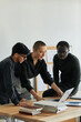 © pressmaster - Group of three ethnically diverse young people wearing casual outfits working together on new project in modern office