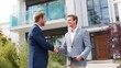 © mila103 - Two real estate agents meet outside a contemporary house, shaking hands and discussing a potential sale as the sun shines. Their professional attire reflects the business setting.