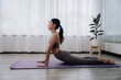 © Kritdanai - Woman Practicing Yoga Cobra Pose Indoors