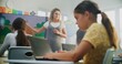 © Framestock - Primary School Girl Creating Illustration on Laptop, Practicing Digital Skills in Modern Classroom. Female Teacher Guiding Young Kids During Art Lesson Using Digital Screen. Creative STEM Learning.