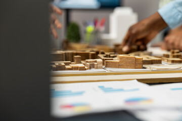 Close up of diverse developers focuses on 3D models layout presentations with detailed city planning for a residential area, waiting for project approval. Infrastructure growth master plan.