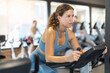© JackF - Woman who has a fitness membership comes to the gym and works out on an exercise bike.