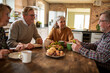 © Marko Geber - Group of senior friends enjoying lunch and conversation together at kitchen table
