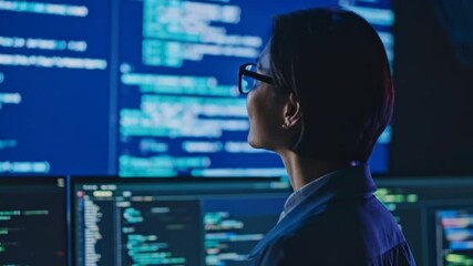Coder with glasses views computer screens