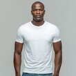 © Surachetsh - A Black man in a plain white t shirt stands against a neutral background. The blank shirt is ideal for clothing mockup and fashion display.